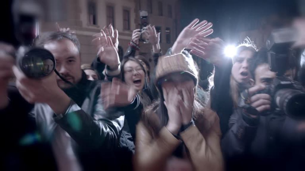 High-drama Hollywood stars surrounded by camera flashes representing the intense media spotlight of celebrity culture